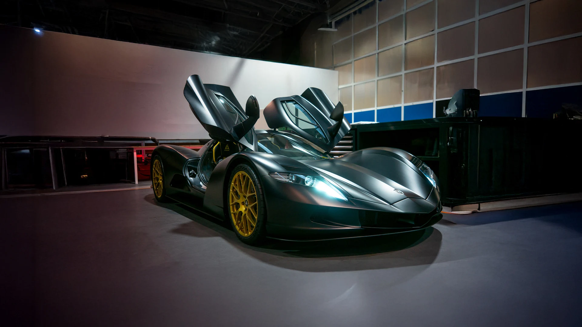 Aspark Owl with open butterfly doors in a dark workshop